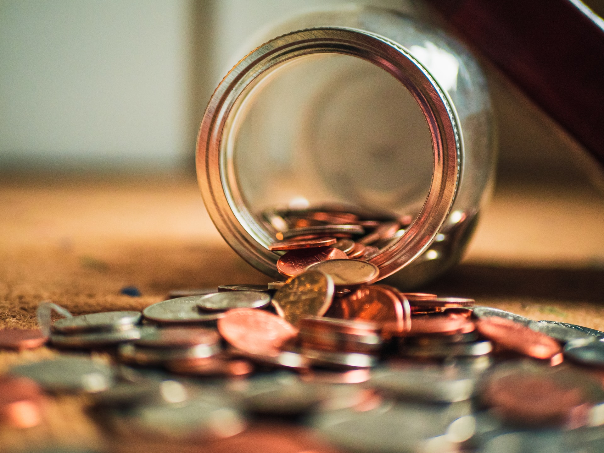 Coins spill from a tipped-over glass jar